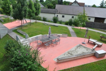 -Sandmulde, Wasserpumpe, Duftbeet und Sitzmöglichkeiten im Therapiegarten.